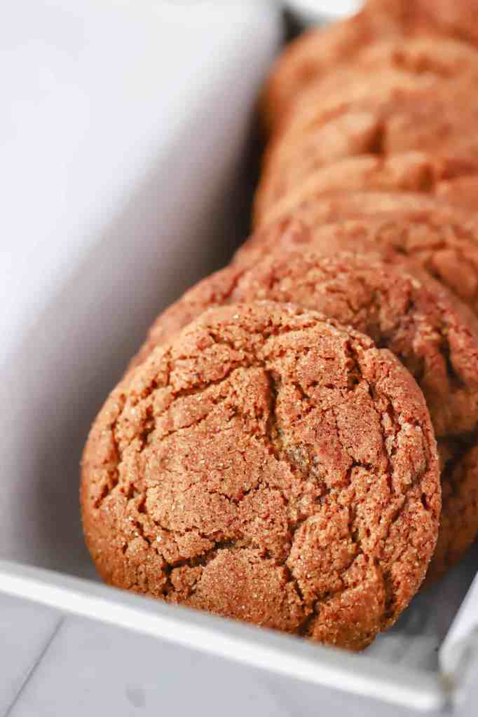 A close up of the chewy ginger molasses cookies in a loaf pan with parchment paper